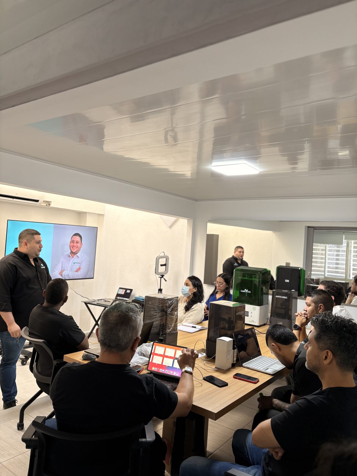 Grupo de asistentes siguiendo la presentación junto a las impresoras 3D
